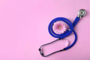 stethoscope and flower on pink background