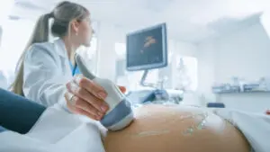 Obstetrician Moving Transducer on the Belly of the Future Mother.