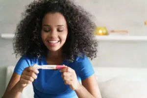 happy woman looking at positive pregnancy test