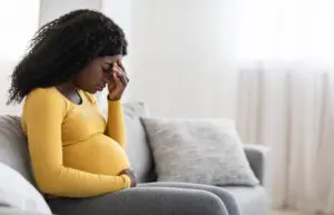 pregnant woman sitting on couch with her eyes closed