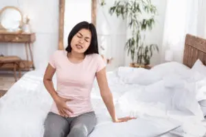 Woman sitting on bed with pelvic pain