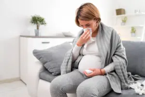 Pregnant woman blowing her nose.