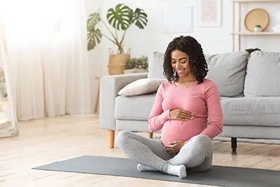 pregnant woman sitting on the floor touching her stomach